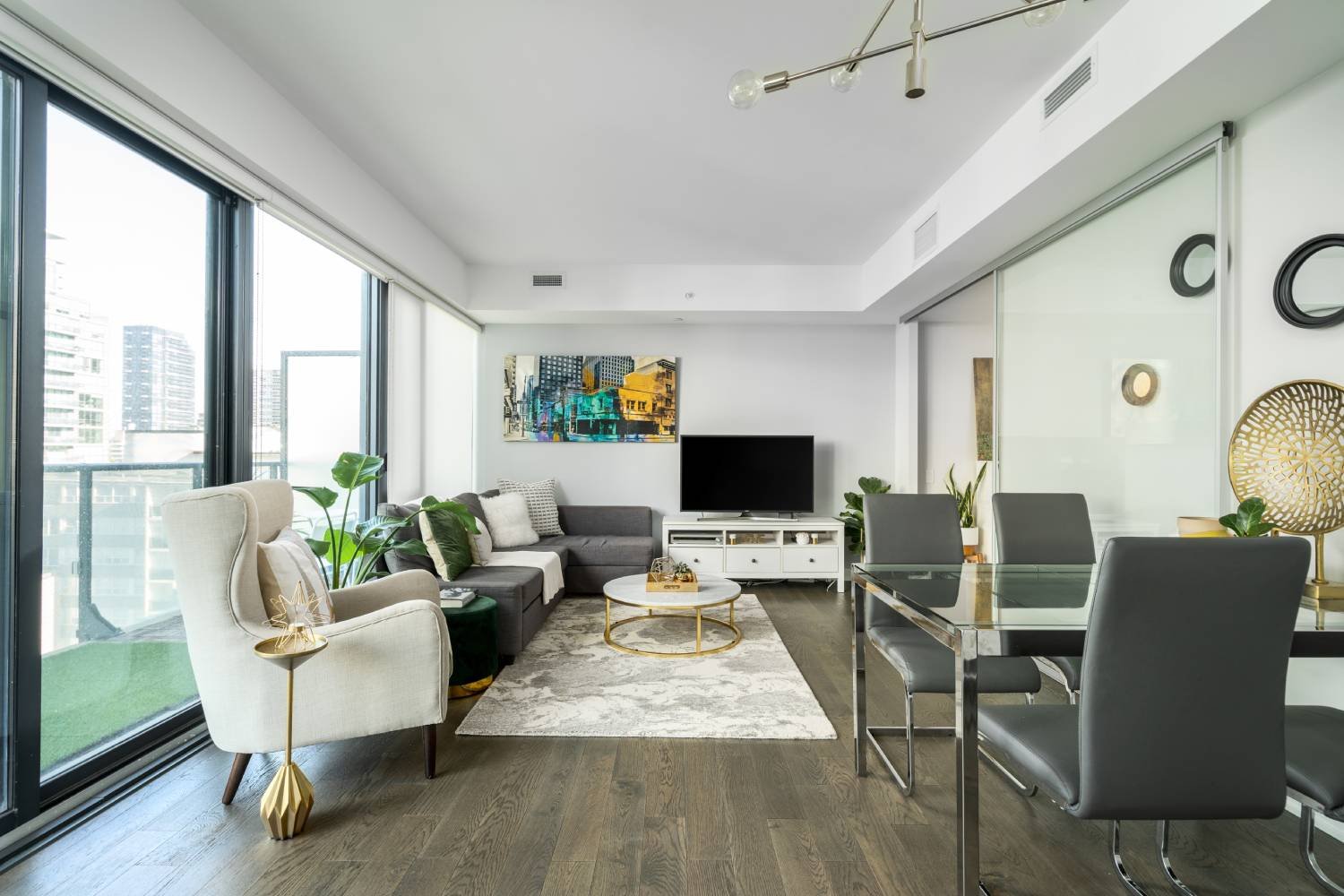 A living room framed by floor-to-ceiling windows and a downtown Toronto view in a home the team has sold